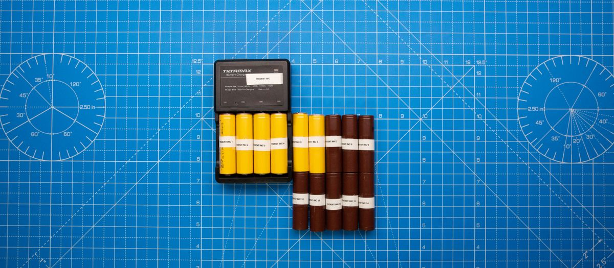 Top view of batteries on a blue grid design surface with a charger, showcasing organization and technology.